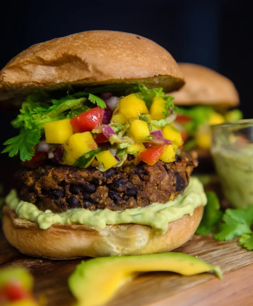 Sensational Black Bean Burgers with Avocado Crema & Mango Salsa 1 Fully assembled Black Bean Burger with vibrant Mango Salsa and creamy Avocado Crema on a toasted bun, ready to eat.